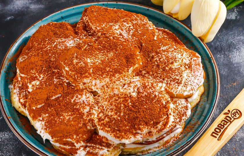 1. Этап. Торт из оладий: Присыпьте приготовленный торт какао-порошком и поместите в холодильник на 1-2 часа для пропитывания.