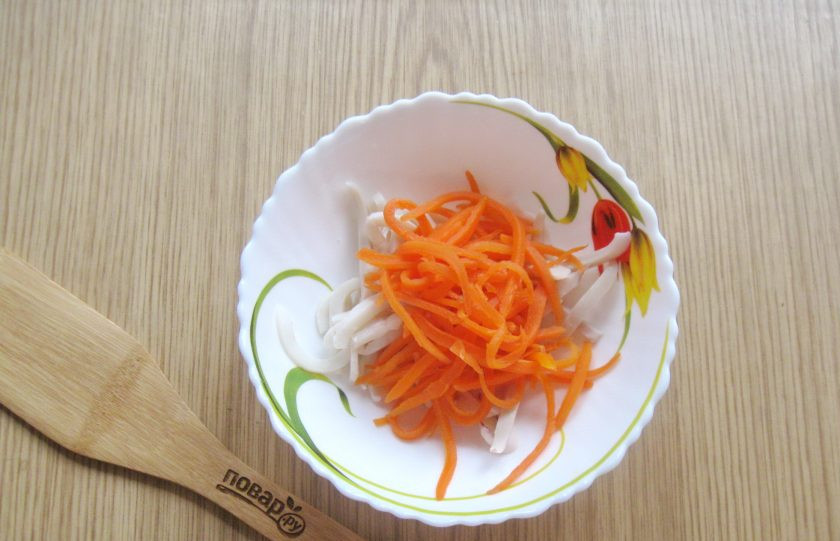 1. Этап. Салат с кальмарами и маринованным луком: Морковь очистите, помойте и нарежьте соломкой, проварите 5-7 минут в кипящей воде. После достаньте, охладите и выложите в салатник с кальмаром.