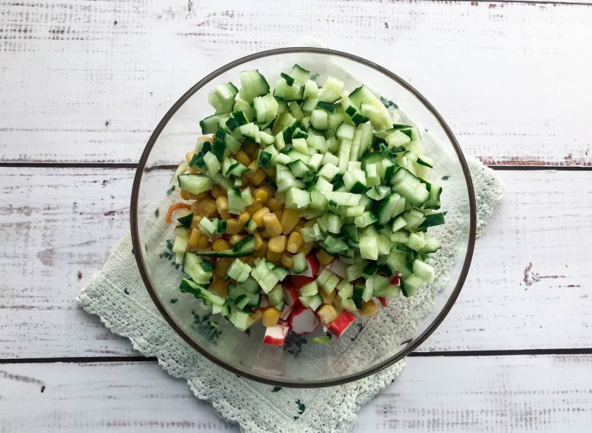 1. Этап. Салат Виктория с крабовыми палочками: Огурец хорошо помойте под проточной водой и мелко нарежьте.