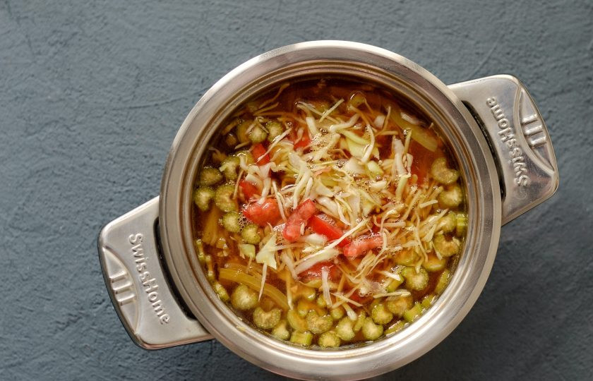 1. Этап. Суп с соевым мясом: Налейте в кастрюлю воду, добавьте соевый соус и бульонный кубик. Доведите до кипения. Затем добавьте мелко нашинкованную капусту и ломтики помидоров. Варите суп 15 минут.