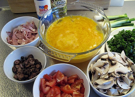 1. Этап. Яичница из страусиного яйца: Подготовьте остальные ингредиенты. Зелёный лук мелко нарубите, оливки и грибы нарежьте тонкими ломтиками. Помидоры маленькими дольками, а ветчину - соломкой.