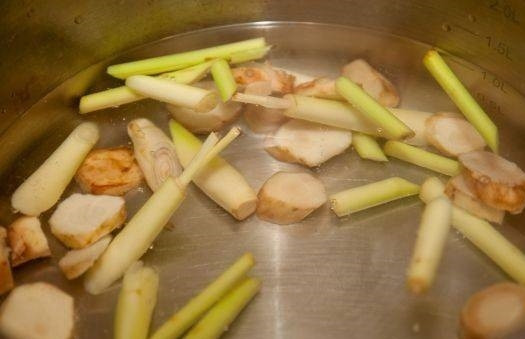 1. Этап. Суп Том ям с креветками: 1. Моем и нарезаем тонкими пластинками галангал, а также лемонграсс нарезаем ломтиками по 3 сантиметра в длину, немного отбиваем его молотком. В кастрюлю наливаем полтора литра воды, добавляем 2 ложки рыбного соуса, порезанные овощи и варим после закипания семь минут.