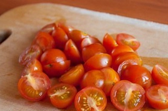 1. Этап. Салат с чечевицей и фетой: Вымойте помидоры под струей холодной воды. Порежьте помидоры черри на четвертинки или пополам, переложите их в салатник к чечевице.