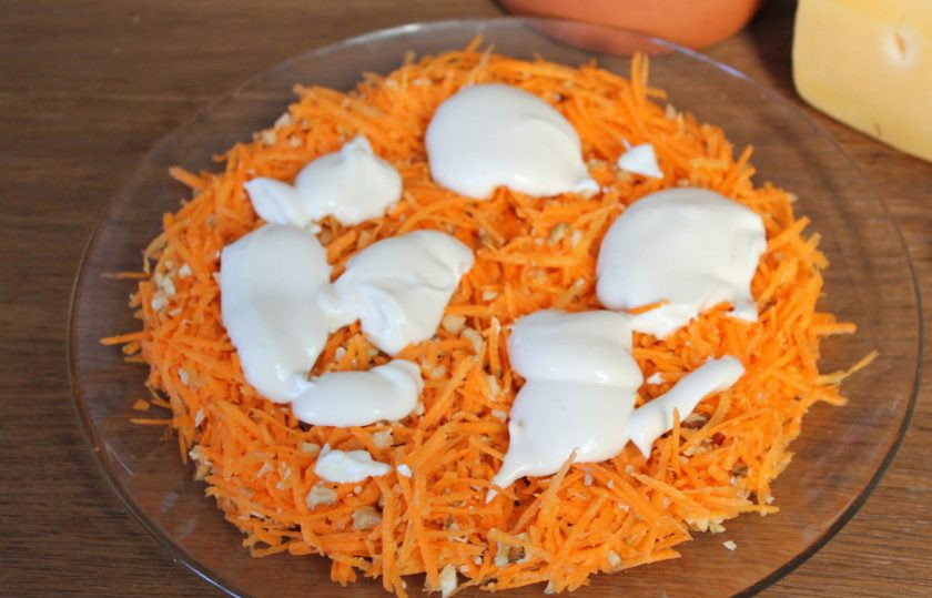 1. Этап. Салат Любовница с черносливом: Морковь с орехами выкладываем на плоскую тарелку и смазываем майонезом.
