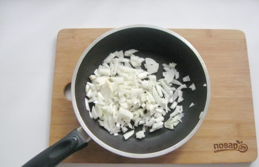 1. Этап. Солянка с солеными грибами: Репчатый лук очистите, помойте и нарежьте мелкими кубиками. Выложите в сковороду.