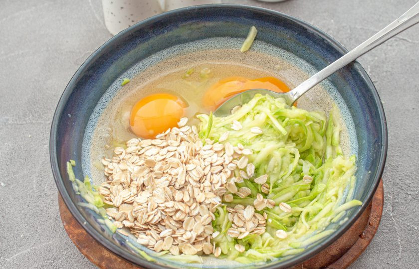 1. Этап. Пицца из кабачков без муки на сковороде: По истечении времени, когда кабачок пустит сок, тщательно его отожмите. Кабачок без сока верните в емкость, добавьте яйца и овсяные хлопья. Хорошо перемешайте все ингредиенты.