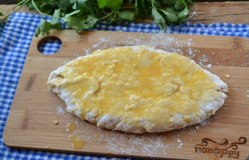 1. Этап. Сырные лепешки на кефире: Заверните тесто, как пирожок. Переверните его и раскатайте каталкой. Смажьте сверху взбитым яйцом.