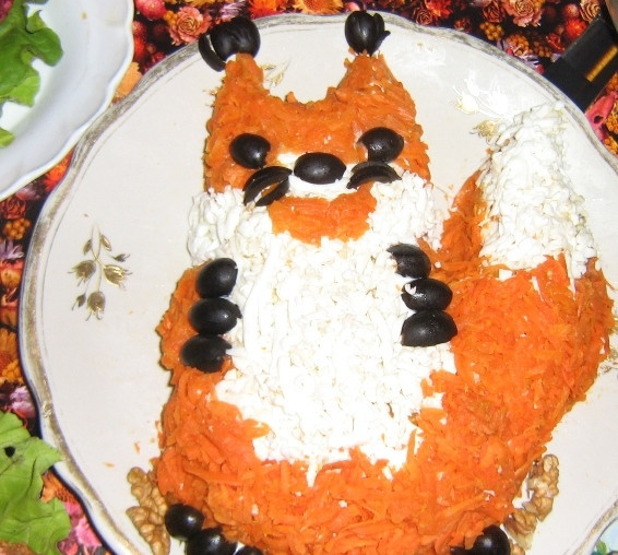 1. Этап. Салат Белочка: Натрите на крупной тёрке варёную морковь, и посыпьте ею салат, как шубку белочки. Лапки и мордочка белочки - из маслин.