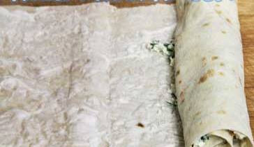 1. Этап. Лаваш с творогом: 4. Теперь лаваш следует завернуть и нарезать небольшими кусочками, ширина которых не должна превышать 20 сантиметров. Одну полосу следует промазать сметаной, после чего только выложить смесь из сыра и зелени на лаваш и равномерно ее распределить по всей поверхности.