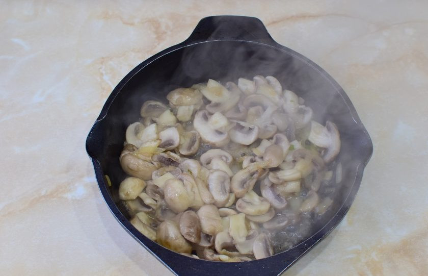 1. Этап. Мясо по-орловски из свинины: Шампиньоны тщательно вымойте от загрязнений, обсушите и нарежьте ломтиками. Лук мелко нарежьте. Обжарьте грибы с луком, примерно 5-7 минут. Долго жарить не надо. Достаточно, чтобы грибы немного уменьшились в размере.