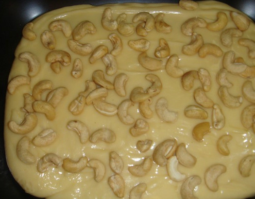 1. Этап. Бурфи из цельного молока: После того, как масса загустеет в кастрюле, перекладываем ее на смазанный маслом противень, либо на пергаментную бумагу. Как вариант — используйте пленку или пакет. Там уже мы формируем массу в квадрат или круг. Можно поделить на кусочки и скатать шарики. Пока масса не застыла, украшаем её орешками. Я взяла для этой цели кешью. Слегка вдавливаем орехи в массу, чтобы они прилипли к ней.