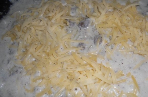 1. Этап. Куриные сердечки в сырном соусе: Сыр натереть на крупной терке и добавить, когда содержимое сковородки начнет закипать. Перемешать и тушить на маленьком огне минут 10. Не забываем помешивать!