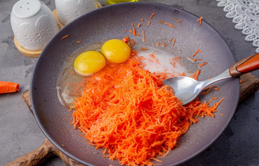 1. Этап. Оладьи из моркови Морковники: Вбейте куриные яйца и влейте молоко. Перемешайте тщательно массу.