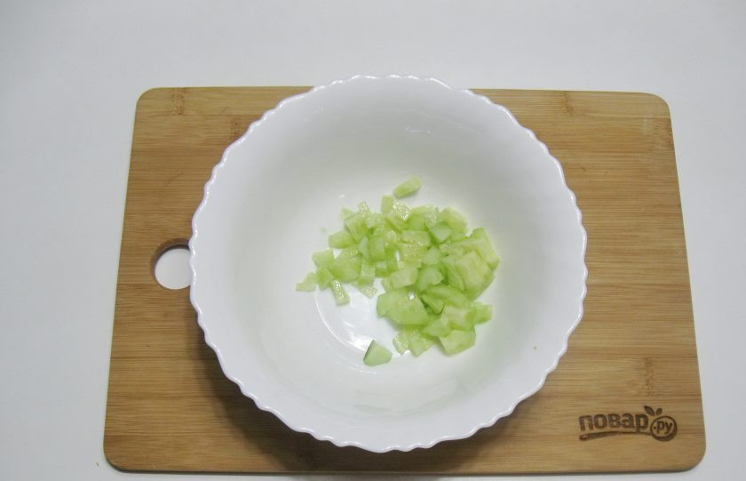 1. Этап. Постный салат с кальмарами: Огурец нарежьте кубиками и выложите в салатник.