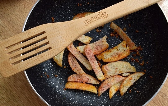 1. Этап. Салат с гренками и сыром: Ломтики багета нарежьте на такие кусочки, чтобы потом было удобно накалывать на вилку. На разогретую сковороду, смазанную маслом, выложите измельченный чеснок. Добавьте кусочки багета, посыпьте паприкой и обжарьте до румяности.