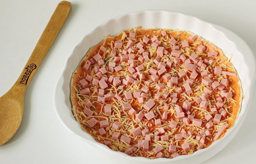 1. Этап. Пицца на слоеном тесте: Посыпьте сверху небольшое количество тертого сыра и положите нарезанную небольшими кубиками и колбасу.