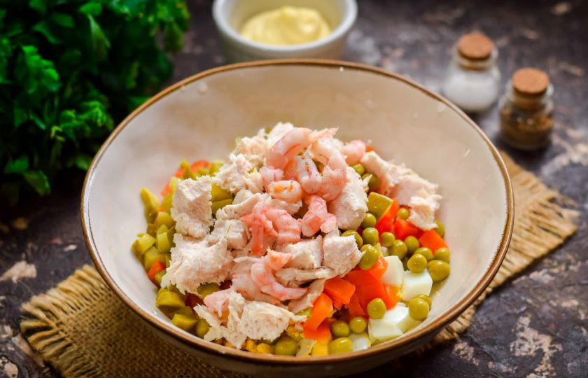 1. Этап. Оливье по-царски: Вареные креветки очистите и добавьте в салат. Нарежьте куриное мясо небольшими кусочками и добавьте в 