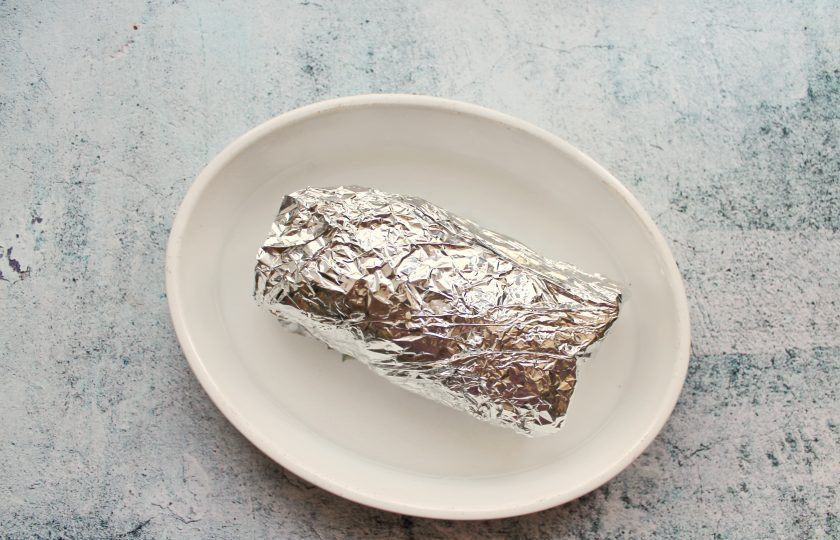 1. Этап. Свинина фаршированная маринованным перцем: Заверните обжаренный рулет в два слоя фольги и выложите в форму для запекания. Налейте в форму немного воды.