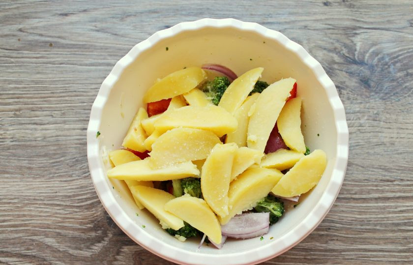 1. Этап. Радужная форель в духовке с овощами: Добавьте в миску с овощами отварной картофель. Влейте растительное масло и аккуратно перемешайте.