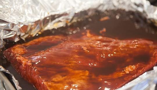 1. Этап. Говядина, запеченная в духовке в фольге: Форму для выпечки застелите фольгой. Выложите в неё говядину. Залейте её смесью из воды, соевого и барбекю соуса.