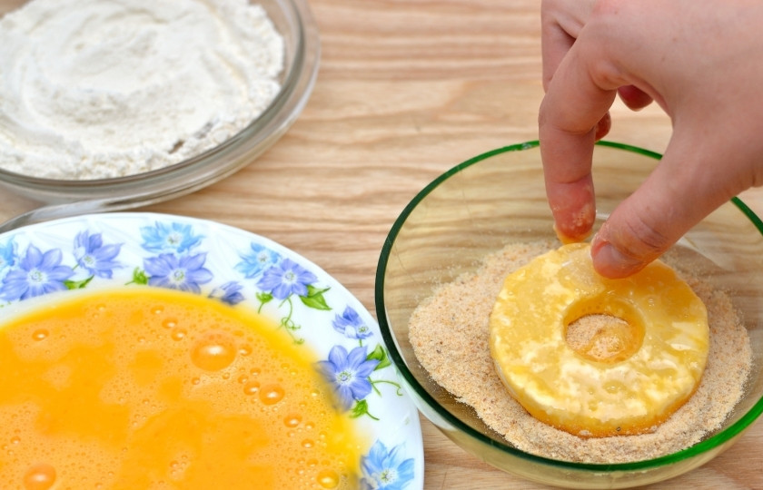 1. Этап. Ананасы в кляре: Сначала изваляйте колечко ананаса в панировочных сухарях, затем в яичной массе, после в муке. И выкладывайте на разогретое растительное масло на сковороде.