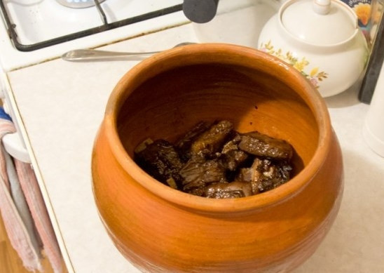 1. Этап. Оленина в горшочке: Выложите мясо оленя в глиняный горшочек, добавьте к нему обжаренные овощи и посолите.