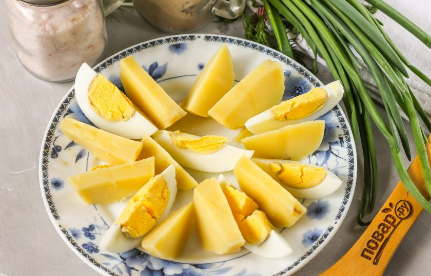 1. Этап. Салат с икрой мойвы: Картофель и куриное яйцо отварите заранее и остудите в воде. Затем счистите с картофеля кожуру, а с яйца - скорлупу и промойте их в воде. Нарежьте дольками и выложите на тарелку.