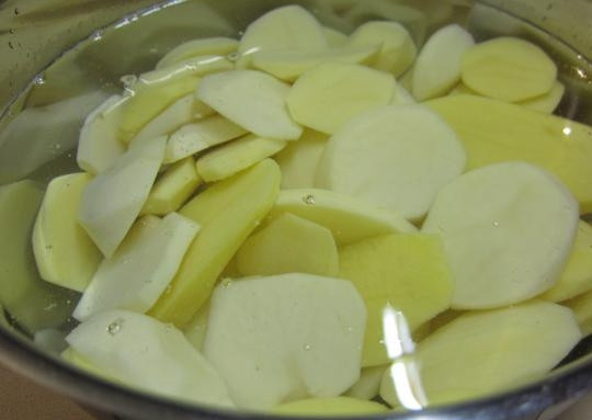 1. Этап. Треска с брокколи в духовке: Картошку помойте, почистите, нарежьте кружочками и поставьте вариться в подсоленной воде. Затем, как только картофель станет полуготовым, слейте жидкость.