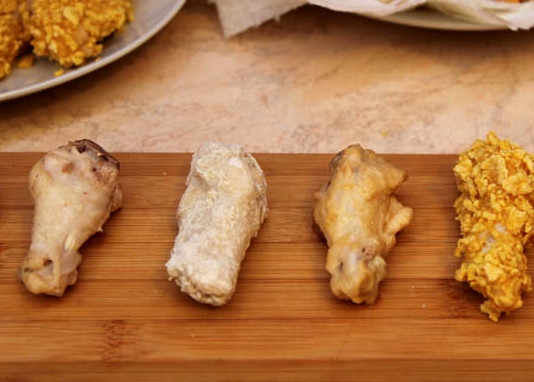 1. Этап. Острые крылья KFC: Приступаем к основной готовке. Каждый кусочек крылышка обваливаем в муке, после чего, обмакиваем во взбитую яичную смесь. В конце обваливаем в слегка раздробленных кукурузных хлопьях. Оставляем крылышки на блюде подсушиться на 20 минут.