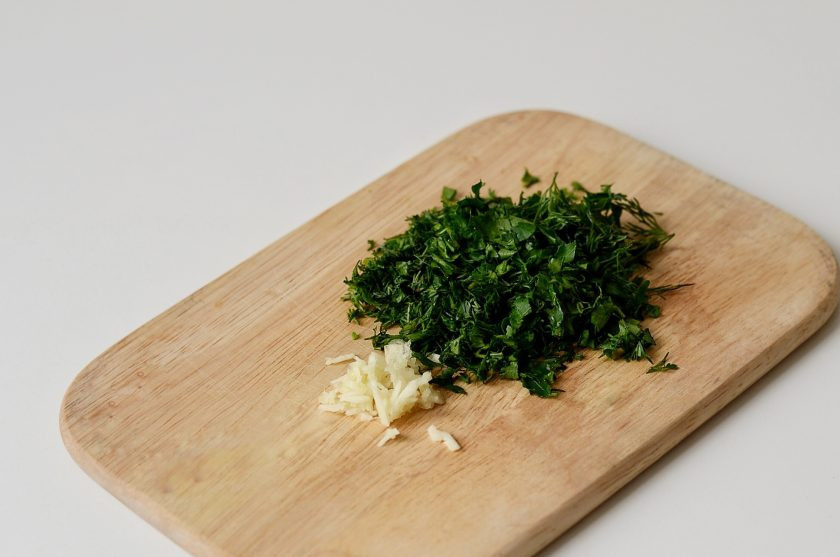 1. Этап. Грузинский салат с баклажанами: Мелко порубите очищенный чеснок и зелень ножом.