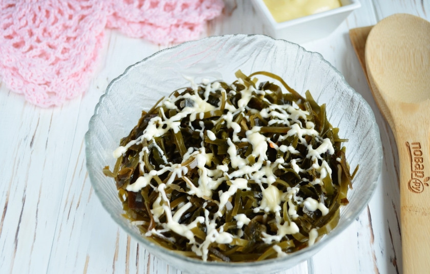 1. Этап. Салат на 8 Марта из морской капусты: Капусту порежьте небольшими полосочками, так удобнее будет кушать салат. На дно салатника положите немного майонеза, далее — капусту и тонкую сеточку из майонеза. Соль в салате не используется.
