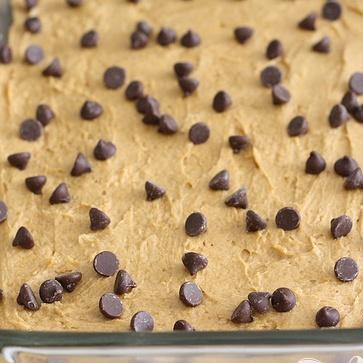 1. Этап. Тыквенные пирожные с карамелью и шоколадом: 2. Выложить 2/3 приготовленного теста в форму и разровнять поверхность шпателем. Посыпать тесто рублеными орехами и шоколадными чипсами.