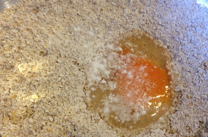 1. Этап. Овсяные оладьи на ряженке: Добавляем в овсянку яйцо.