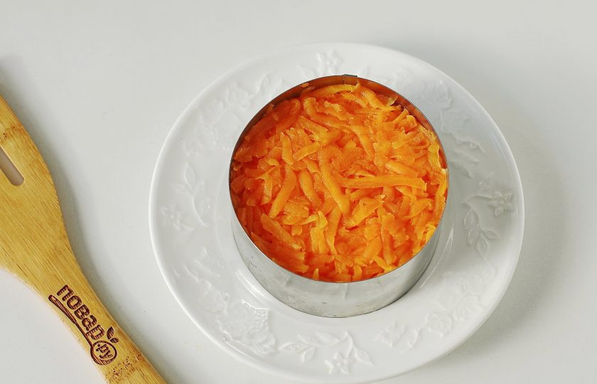 1. Этап. Салат Мимоза с грибами: Смажьте слой майонезом и равномерно распределите тертую на крупной терке морковь.