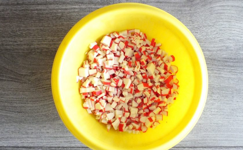 1. Этап. Крабовый салат в тарталетках: Крабовые палочки нарежьте мелким кубиком и переложите в чашу.