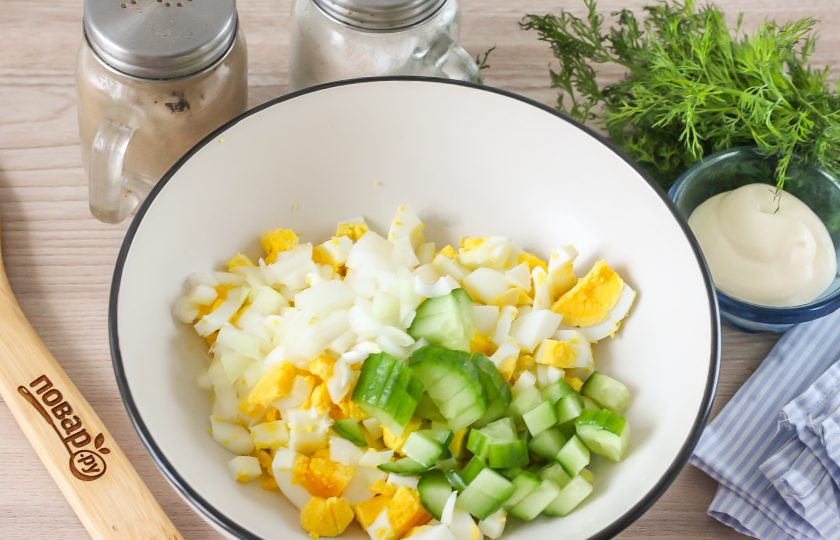 1. Этап. Салат с консервированной горбушей и яйцами: Промойте половину репчатой луковицы и огурца, нарежьте их такими же кубиками и добавьте в емкость.
