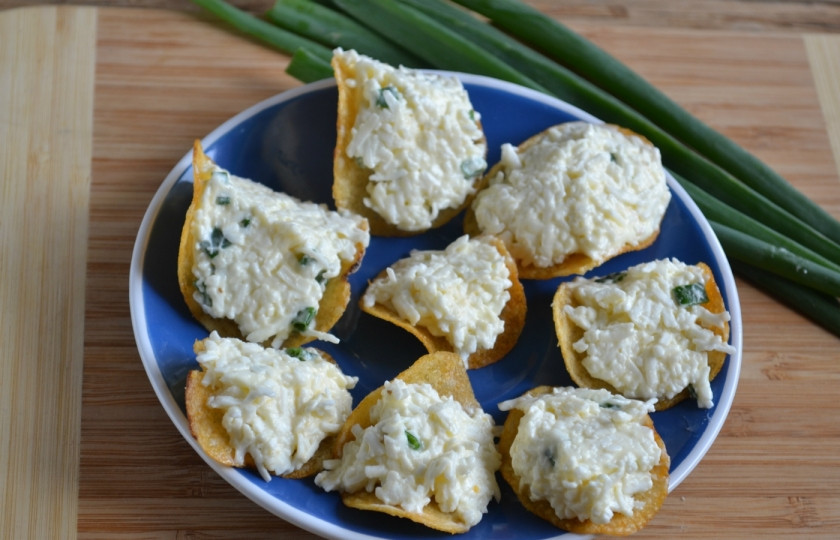 1. Этап. Закуска на чипсах: Положите по половине столовой ложки сырной массы на чипсы. В идеале используйте чипсы Pringles, но подойдут и обычные в пачке. Через 10-15 минут чипсы слегка размякнут благодаря майонезу, тогда и можно подавать закуску к столу.