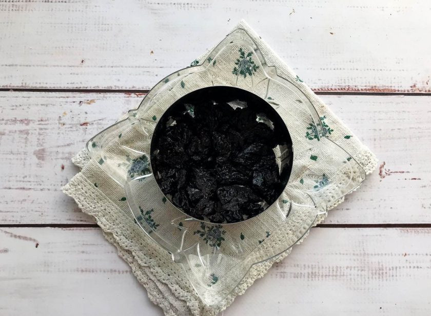 1. Этап. Салат с ветчиной и грецкими орехами: Чернослив хорошо вымойте и нарежьте небольшими кусочками. На тарелку выложите кулинарное кольцо и сделайте нижний слой из чернослива.