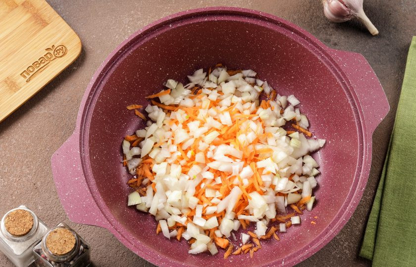 1. Этап. Курица с картофелем и морковью: Для приготовления возьмите казан или глубокую сковороду с толстым дном. Налейте масло, разогрейте его и выложите нарезанный кубиками лук и тёртую морковь.