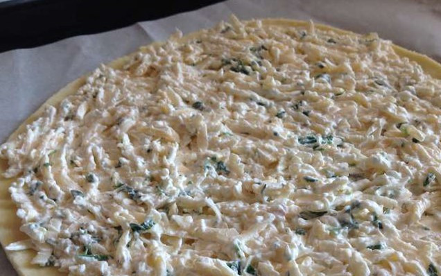 1. Этап. Хачапури из творожного теста с сыром: Застелите противень пергаментом, выложите одну лепешку и равномерно распределите сыр по поверхности.