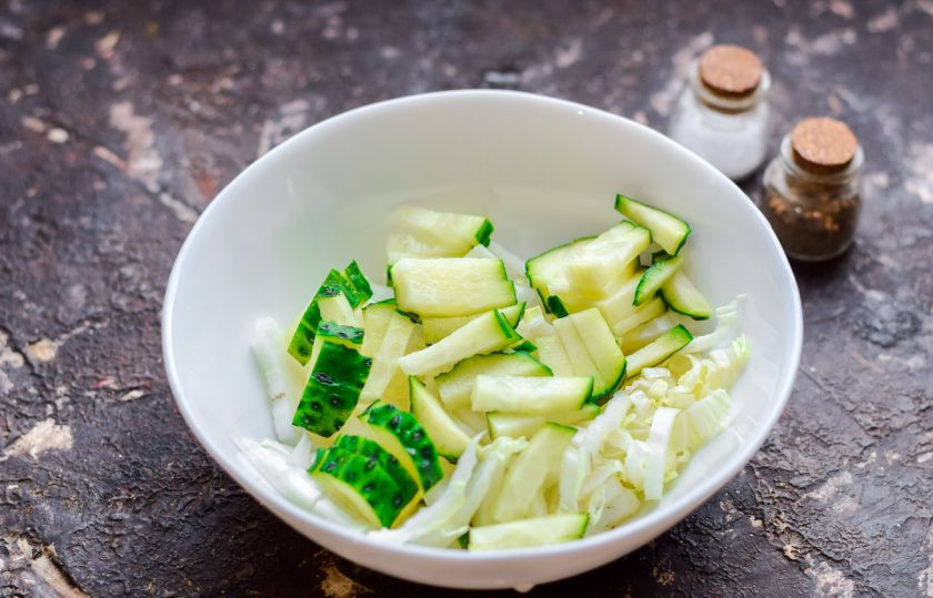 1. Этап. Салат Яркий праздник с курицей: Огурец сполосните и просушите, нарежьте небольшими полосками или кубиками. Добавьте огурец к капусте.