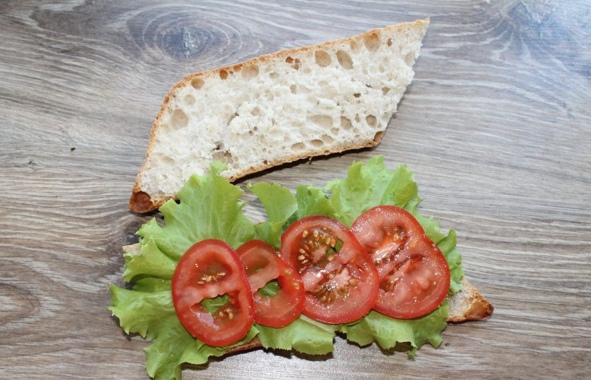 1. Этап. Греческий сэндвич: Помидор порежьте кружочками и выложите внахлест на листья салата.