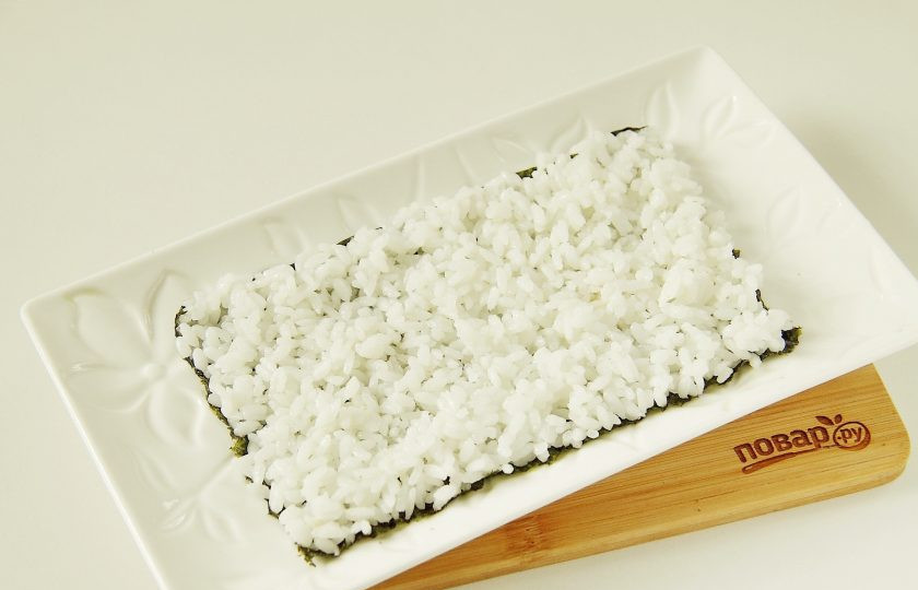 1. Этап. Салат Суши: Мокрыми руками аккуратно распределите сверху рис небольшим слоем.