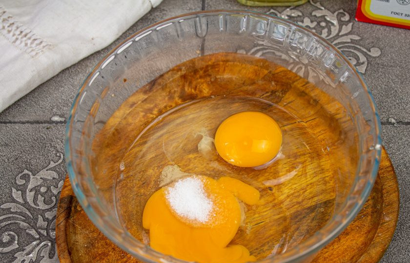 1. Этап. Кето-хлеб: В подходящую миску вбейте куриные яйца, добавьте соль. Перемешайте венчиком.
