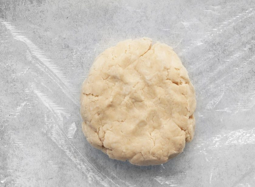 1. Этап. Галета с черникой и сливочным сыром: 3. Вливайте в мучную крошку по столовой ложке холодной воды, затем соберите тесто в единый ком и оберните его в пленку. Отправьте тесто на 1 час в холодильник.