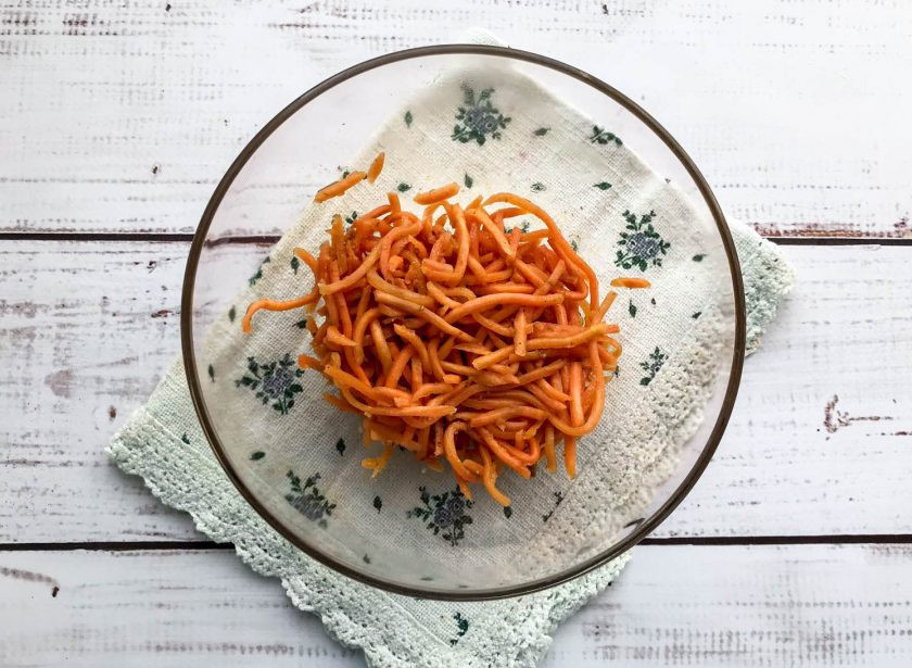 1. Этап. Салат Виктория с крабовыми палочками: Морковь по-корейски выложите в глубокую тарелку.