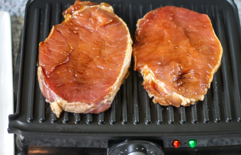 1. Этап. Стейк на электрическом гриле: Раскалите электрический гриль. По желанию стороны гриля можно смазать растительным маслом. Выложите на гриль стейки, прижмите второй частью и обжаривайте от 5 до 8 минут в зависимости от мощности техники и толщины мяса.