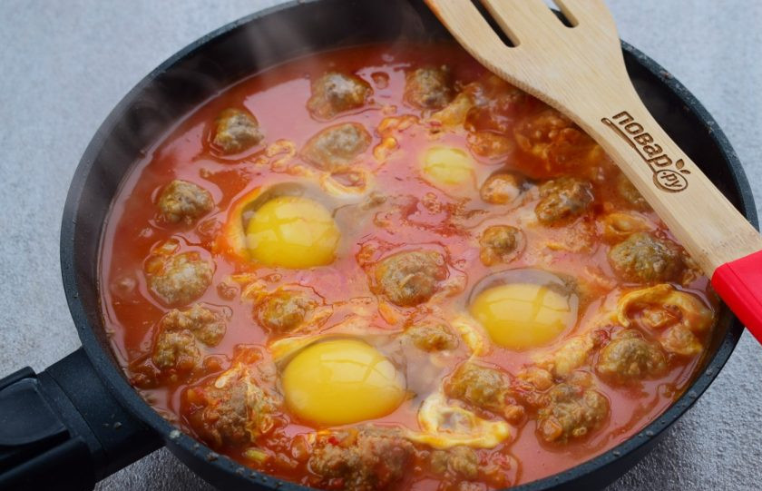 1. Этап. Фрикадельки с томатным соусом и яйцом: Вбейте в соус четыре яйца, готовьте 5 минут.