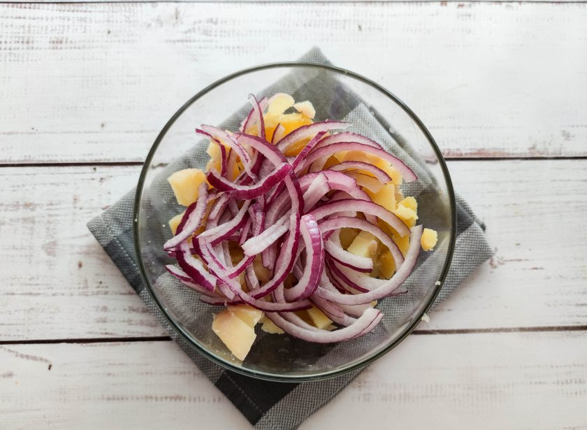 1. Этап. Салат с картофелем и копченой скумбрией: Лук очистите от шелухи, нарежьте полукольцами и выложите в тарелку.