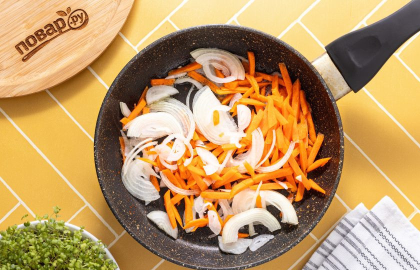 1. Этап. Салат из фунчозы и китайских древесных грибов: Репчатый лук нарежьте полукольцами, а морковь очистите и натрите на терке для моркови по-корейски. Разогрейте сковороду с растительным маслом и обжарьте овощи на умеренном огне 2-3 минуты.